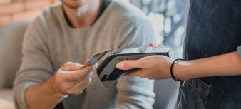 Person holding credit card next to card reader.